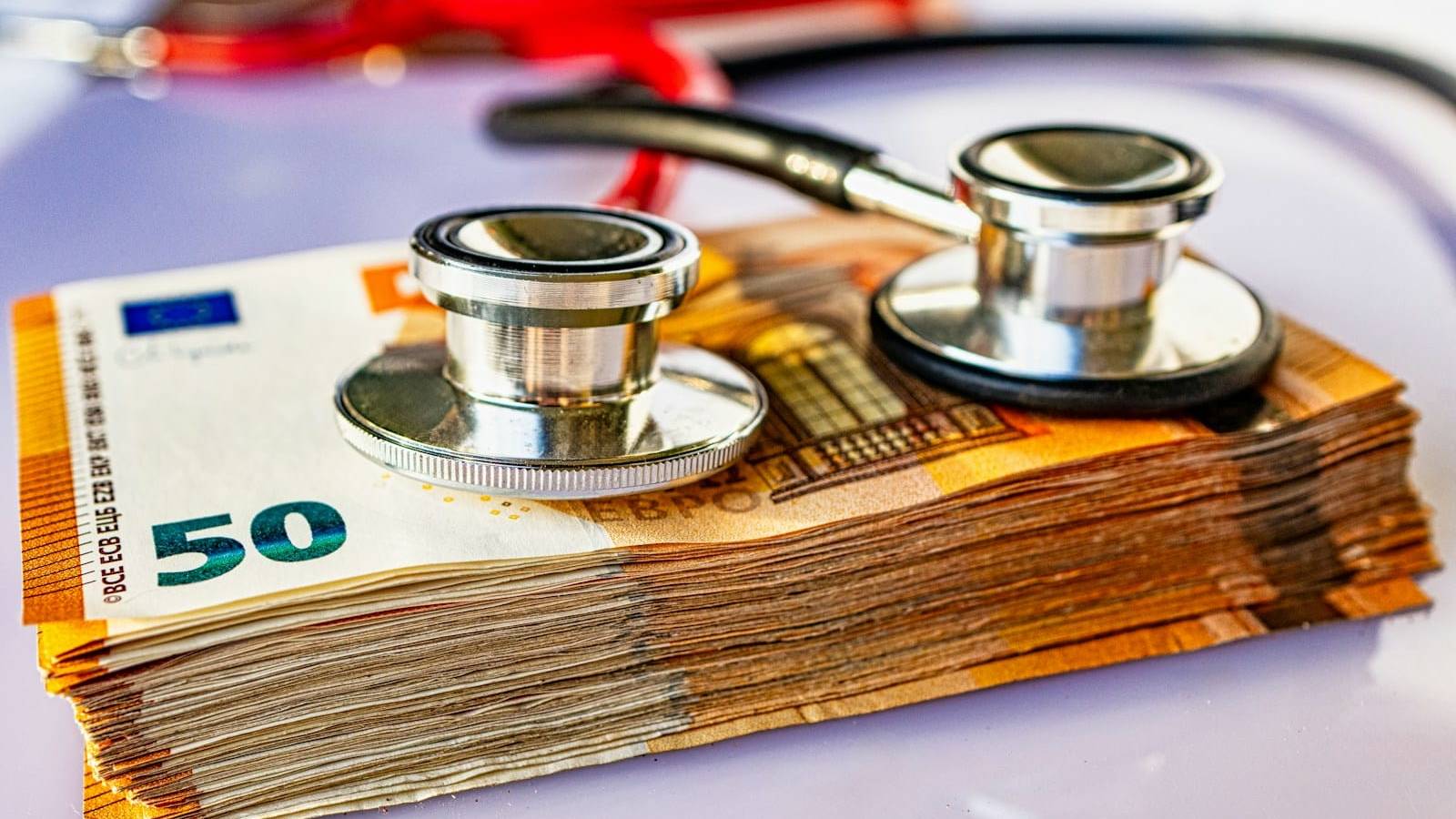 a pile of money with a stethoscope on top of it